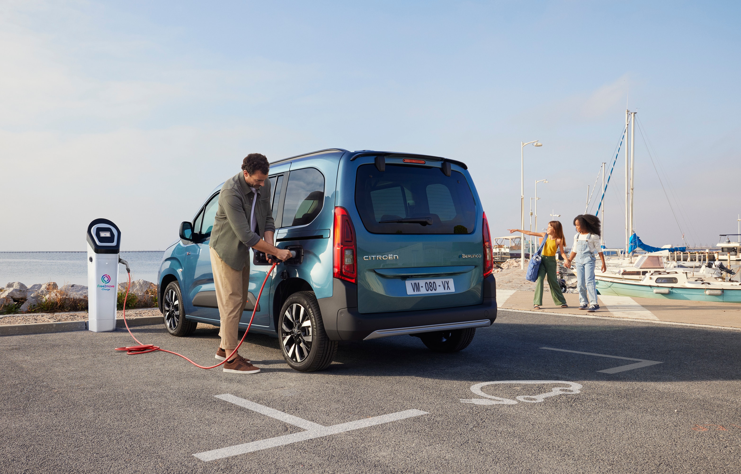 Man charging ë-Berlingo in front of the sea