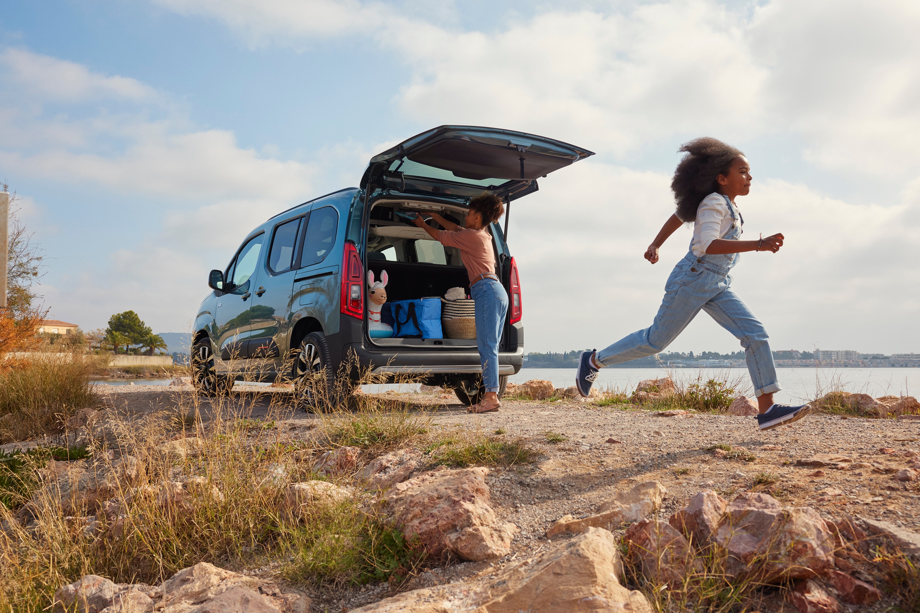 woman loading ë-Berlingo trunk in front of the sea